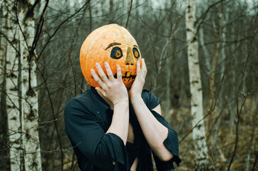 Halloween Scarecrow with a pumpkin on its head has her hands pressed to her cheeks and is terrified