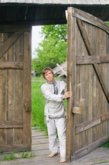 guy in old clothes opens a large wooden gate
