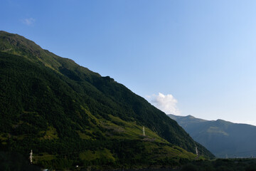 Fototapeta premium View of the beautiful countryside of North Ossetia. Sunny day. Beautiful summer landscape in the mountains. Grassy fields and hills. Rural landscapes