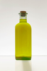 GOLDEN OLIVE OIL GLASS BOTTLE WITH CORK ON WHITE BACKGROUND. FRONT VIEW.