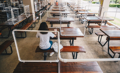Rear view of woman sitting on wooden table with group of plastic partition setting on table in...