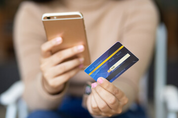 Yong female hand holding plastic credit card and using laptop. Online shopping or paying concept.
