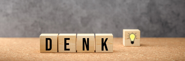 cubes showing German message for THINK and a lightbulb symbol on concrete background