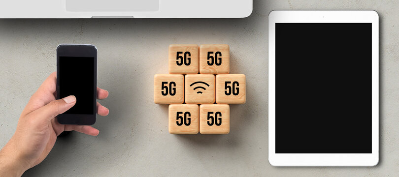 cubes with 5G and WLAN symbol besides tablet, smartphone, and laptop on concrete background