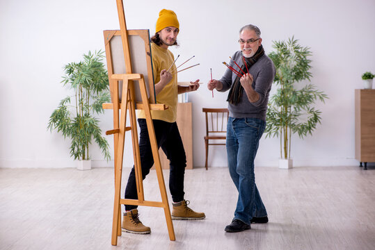 Old man taking lesson from young painter
