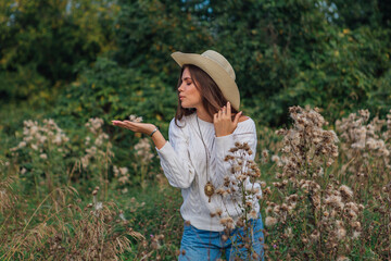 Young beautiful brunette woman standing in the grass, smiling and touching her hair