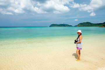 Obraz na płótnie Canvas 沖縄県　西表島の船浮のイダの浜を撮影中の女性写真家