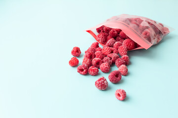 Storing fresh raspberries in freezer bags. Frozen berries on a blue background.