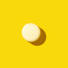 One colorful french cookie macaron yellow colored. Minimal concept, monochrome image. Hard light