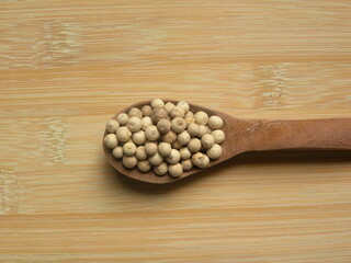 White color raw whole dried pepper on wooden spoon