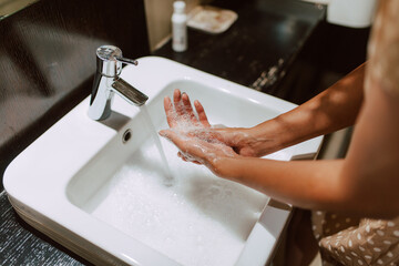 Top view of woman hands while washing hands with soap in the bathroom. Prevention of COVID - 19 coronavirus