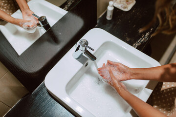 Top view of woman hands while washing hands with soap in the bathroom. Prevention of COVID - 19 coronavirus