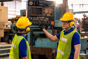 Professional technicians are demonstrating machine control operations with a remote control in an industrial factory.