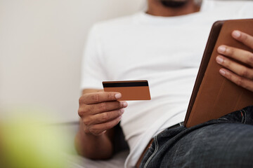 Close-up image of Black man using credit card to pay for online purchases and services