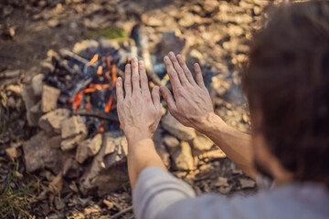 man warming his hands by a fire. Poor men warm outdoors near smoking barre