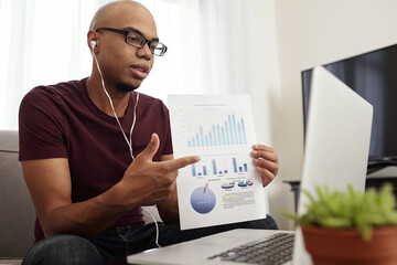 Fototapeta na wymiar Young African-American financial analyst showing report to colleagues during online conference