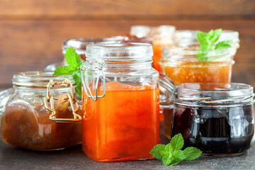 Various jars of fruit jam on dark table. Selective focus