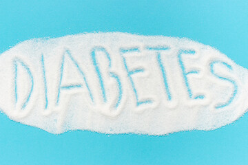 Word diabetes laid out from sugar isolated on a blue background