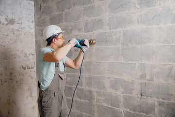 Builder worker pneumatic hammer drills hole in concrete brick wall with diamond crown for electric...