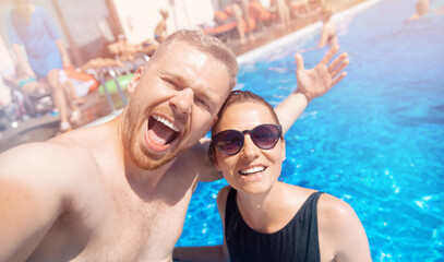 Couple happy caucasian beautiful young woman and man make selfie photo on background swimming pool. Concept travel summer trip