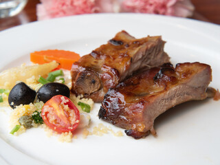 Pork ribs grilled with BBQ sauce and caramelized in honey served with a side dish on a white plate. Close up of barbecue beef ribs with bbq sauce sliced.