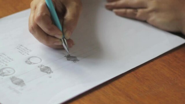 A hand drawing and making sketch with a pen. A jewelry designer makes outlines on paper.