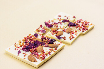 A broken bar of white chocolate with dried berries, candied fruits and almonds.