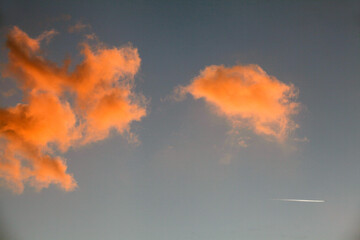 07-03-2015 Lerchi - Perugia (Italy).A plane leaves a white trail in the sky with orange clouds.