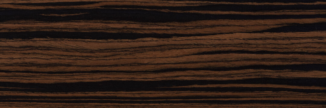 Unique ebony veneer background in dark color. Natural wood texture, pattern of a long veneer sheet, plank.