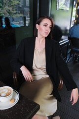 pensive or thoughtful woman sitting at table in cafe wearing black jacket - 368936220