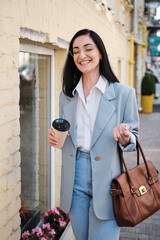 laughing businesswoman holding cofee in urban background - 368936474