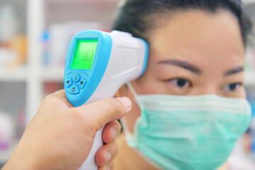 Doctor's hand checking woman with infrared digital thermometer in hospital.
