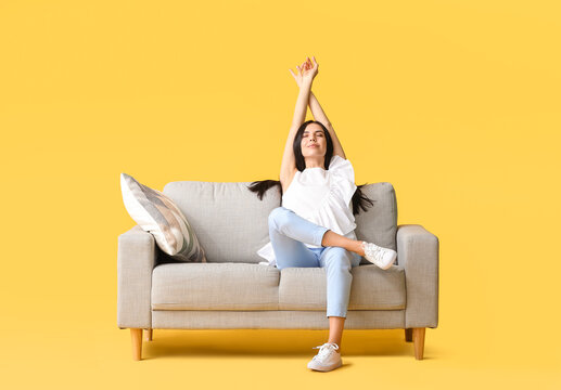 Young Woman Relaxing On Sofa Against Color Background