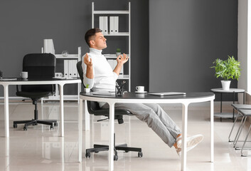 Young man meditating at workplace in office