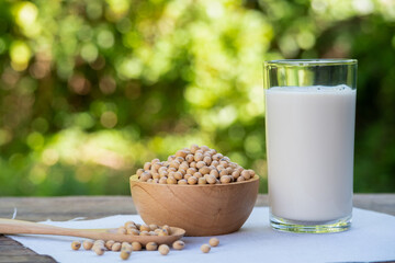 Soybeans in wooden bowl and soy milk in glass on wood table.with blur nature background