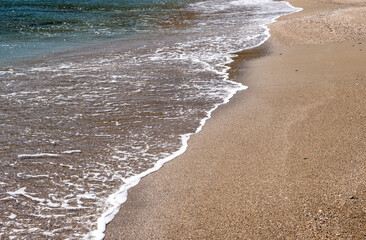 Sandy beach, ripples rolling on the coast, calm sea water background
