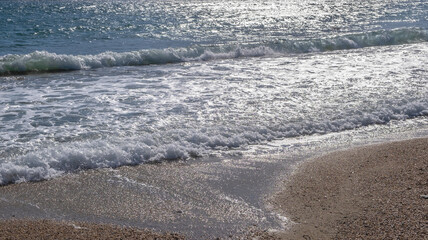 Sandy beach, ripples rolling on the coast, calm sea water background