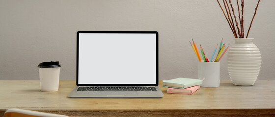 Computer laptop with clipping path on wooden table with stationery, paper cup and decoration