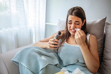 Young woman making a face of disgust at a spoon full of cough syrup. Exhausted young woman...
