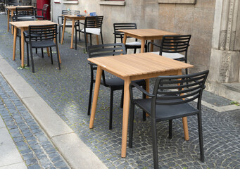 empty tables and chairs outdoors in front of a restaurant