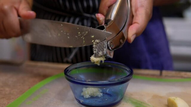 Adding crushed garlic to a bowl in preparation for a homemade dish - slow motion