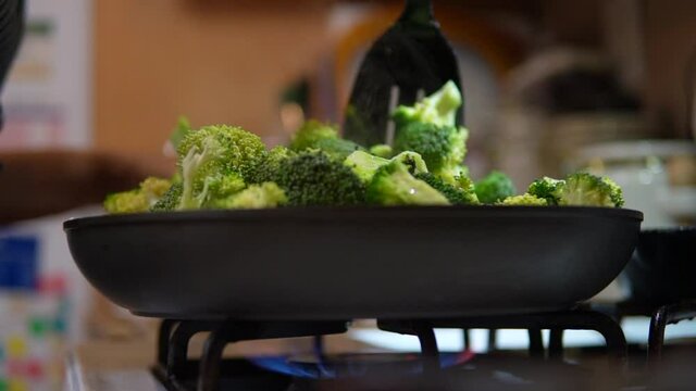 Stirring broccoli on the stove top for a homemade meal - slow motion low angle