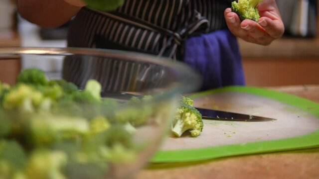 Cutting and pulling broccoli apart for a healthy meal or snack - focus pull from cutting board to bowl