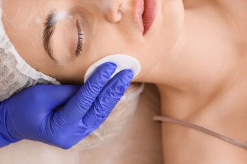 Woman undergoing procedure of facial peeling in beauty salon, closeup