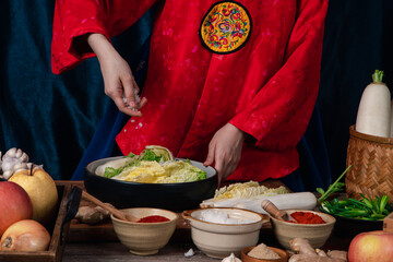 Asian women wearing Korean traditional costumes (hanbok) are Sprinkling salt by hand and Kimchi ingredients with ingredients such as garlic, gochugaru (Korean chili), fresh vegetables.