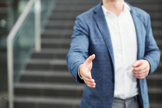Close-up image of businessman outstreching arm for handshake