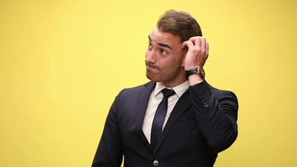 confused elegant businessman in suit looking around scratching head and thinking, having an idea and pointing finger, smiling and standing on yellow background