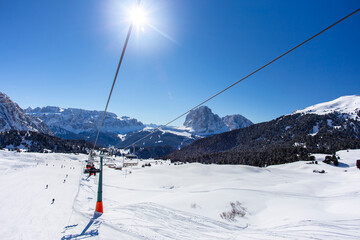 Fototapeta na wymiar Cable car with tourists, view of the mountain peaks, around a lot of snow and bright spring sun in the resort of Val Gardena Italy 
