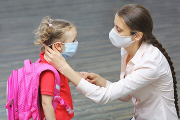 A mother puts on medical mask for her little daughter