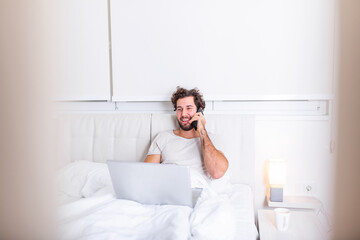 Photo of focused pensive young guy entrepreneur have weekends work use his laptop to make report boss wants lying on bed in house indoors. Man working from home
